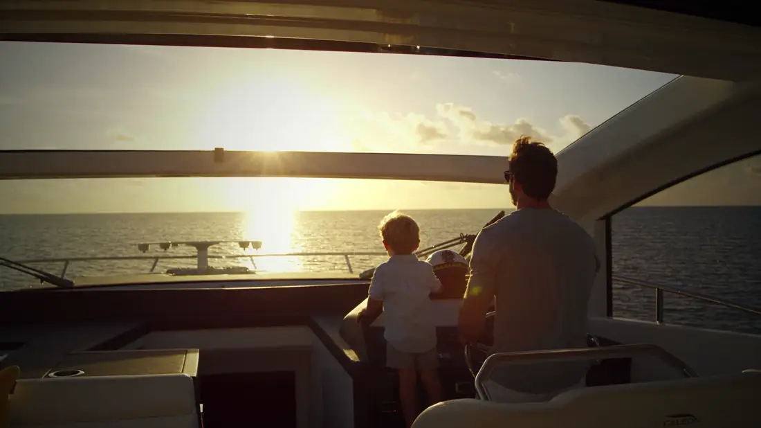 An adult and a child at the bow rail watching the sunset